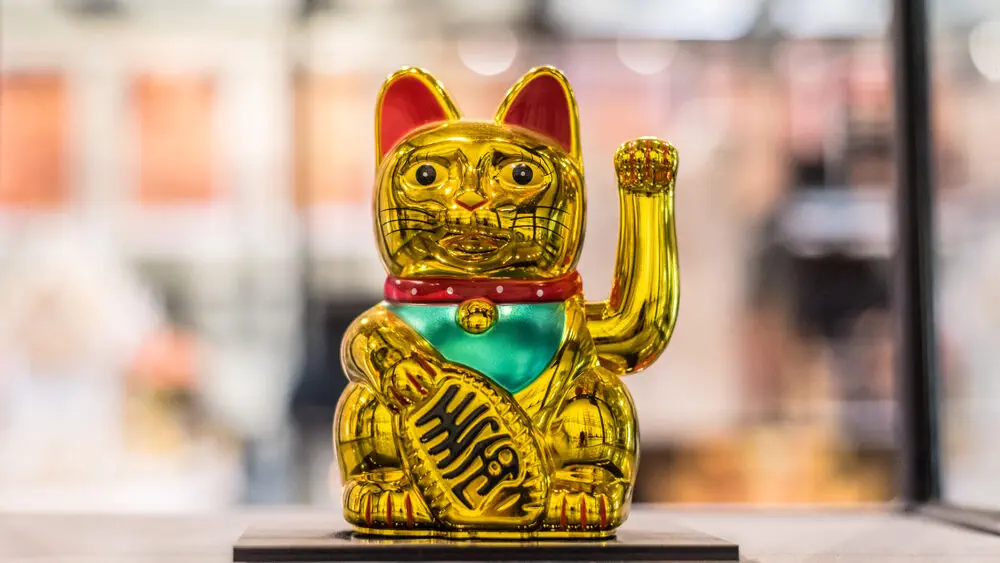 Goldene Maneki-neko-Figur mit erhobener Pfote – japanisches Symbol für Glück, Wohlstand und Schutz